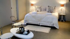 A bedroom with a large bed, two bedside tables, a small round table with a tray, and a door. - The duBoirs Boutique Lodge (Waterfall)