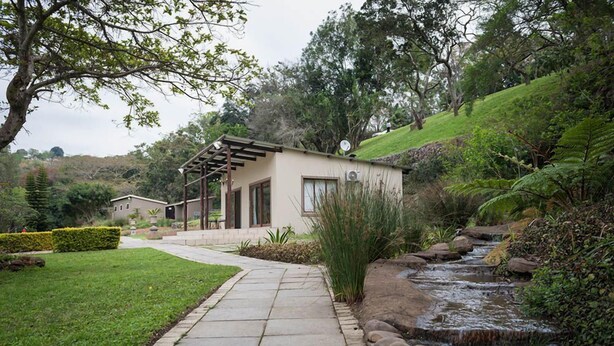 A modern house with a covered patio, a small garden, and a stream. - The duBoirs Boutique Lodge (Waterfall)
