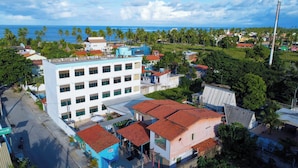 A multi-story building with a flat roof and a large window on the ground floor. - Pousada Sal e Mar (Ipojuca)