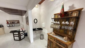 A kitchen with a black countertop, a wooden cabinet with glassware, and a decorative wreath on the wall. - Pousada Sal e Mar (Ipojuca)