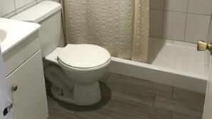 Et badeværelse med toilet, vask og bruseområde.