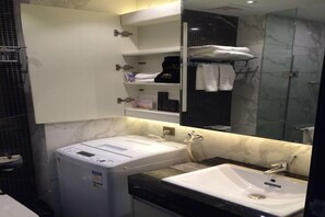 A modern bathroom with a built-in washing machine, a sink, and a mirror. - Kanglaibo Boutique Hotel Ganzhou (Ganzhou)