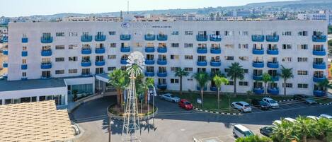 A hotel with a modern design, featuring a central courtyard with palm trees and a windmill.