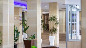 A hotel lobby with a reception desk, potted plants, and a staircase leading to an upper floor. - Tetyk Hotel  (Paralimni)