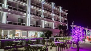 A multi-story hotel with outdoor seating and a brightly lit facade. - Santa Quaranta Premium Resort (Sarandë)