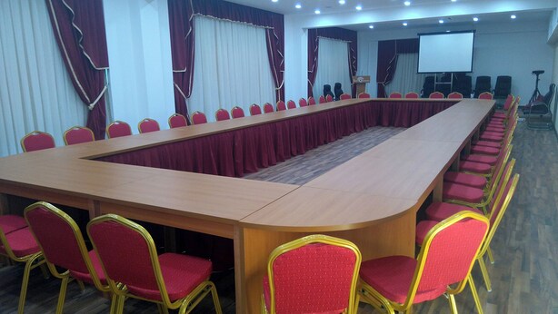A conference room with a long table, red chairs, and a projector screen. - Santa Quaranta Premium Resort (Sarandë)