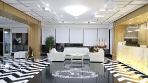 A modern lobby with a central seating area, a reception desk, and a decorative floor pattern. - Santa Quaranta Premium Resort (Sarandë)