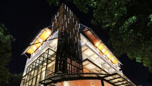 A modern building with a glass facade, a central atrium, and outdoor seating area. - Hay Bandung (Bandung)