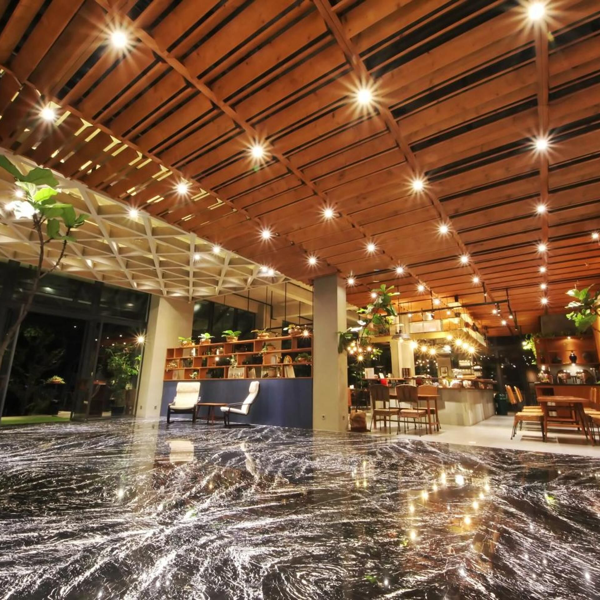 Un vaste espace intérieur doté d’un plafond en bois, d’un sol en marbre et de différents types de sièges.