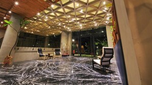 An indoor area with a ceiling featuring a geometric pattern, seating arrangements, and a floor with a marble-like texture. - Hay Bandung (Bandung)