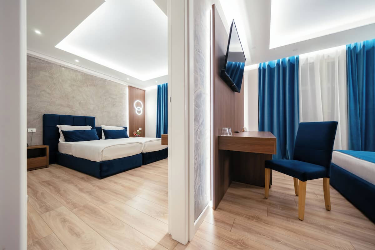 Una habitación de hotel moderna con una cama, escritorio, silla y televisor montado en la pared.