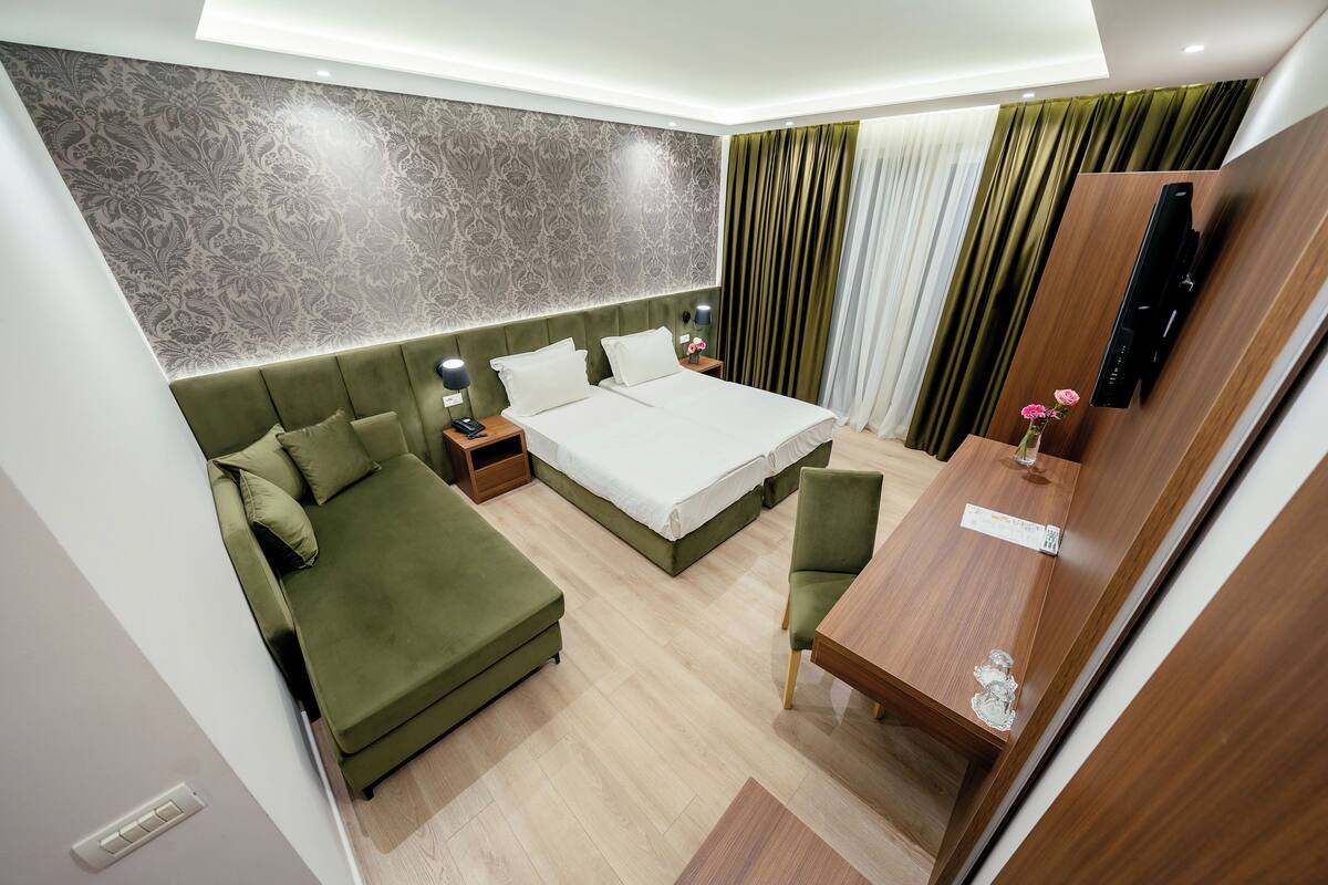 Una habitación de hotel moderna con una cama grande, un sofá, un escritorio y un televisor.