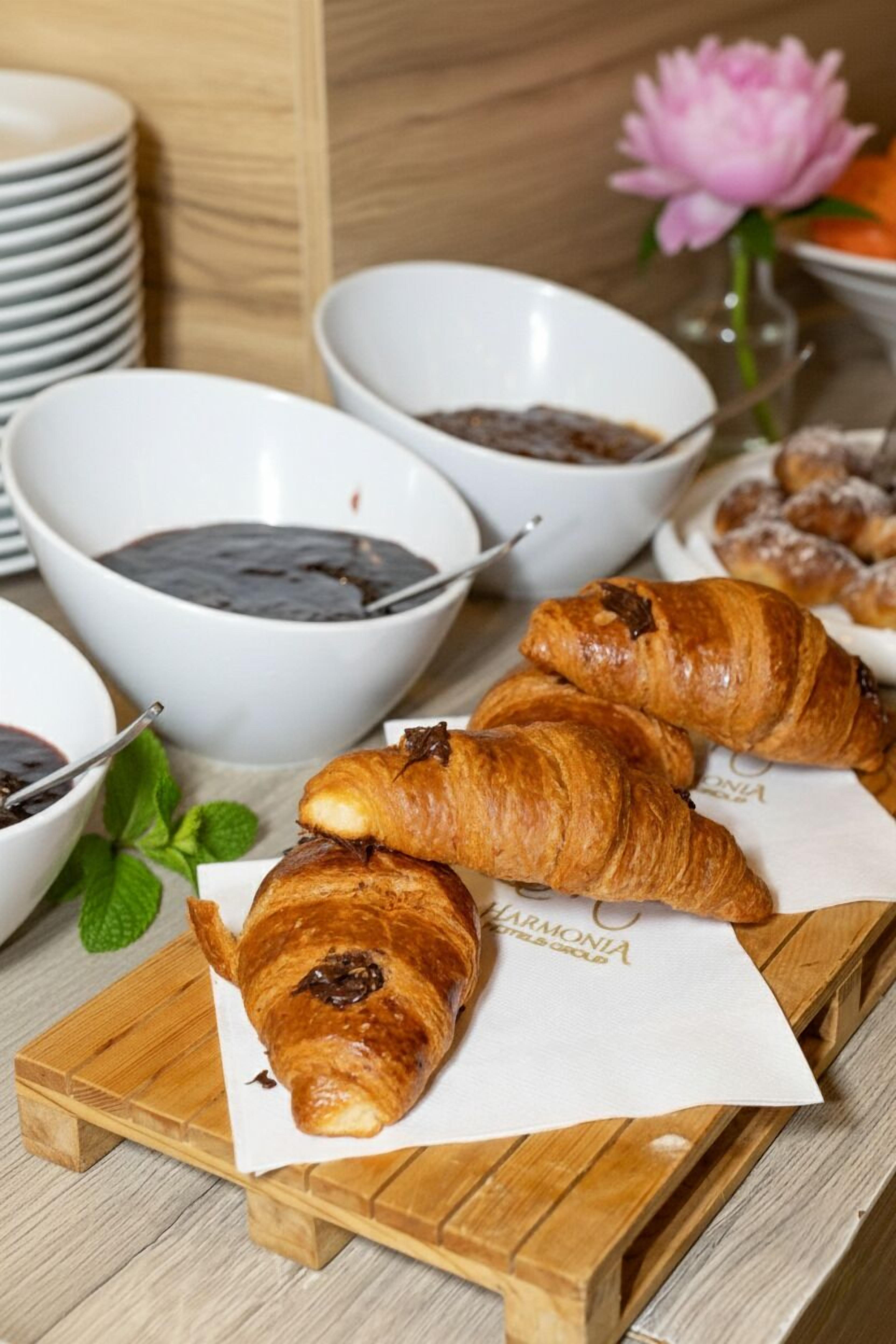 Una mesa de madera con croissants y recipientes de salsa de chocolate.