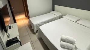 Une chambre d’hôtel avec deux lits simples, un bureau avec une chaise, un téléviseur à écran plat et un climatiseur mural.