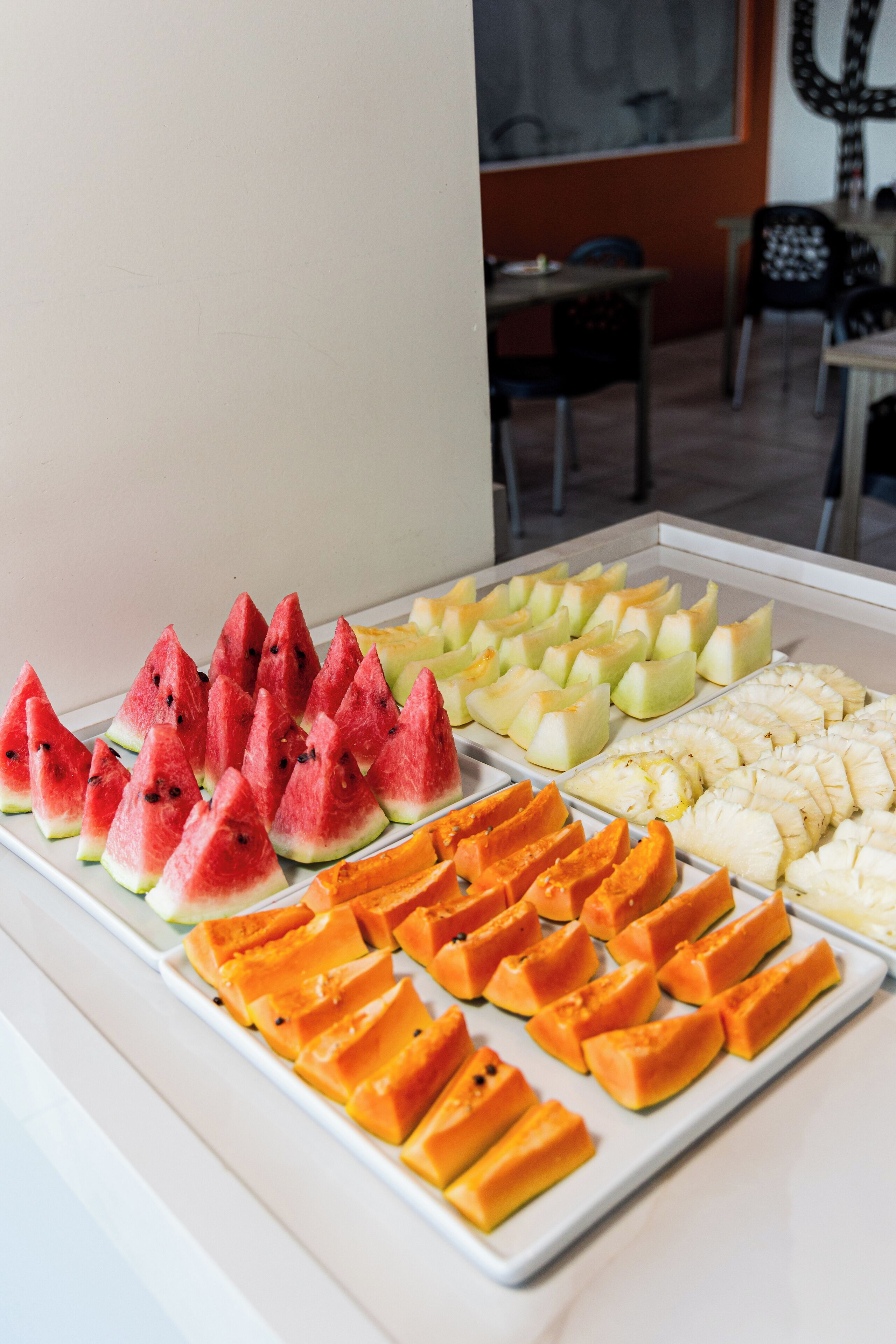 A fruit display with various types of sliced fruits arranged on a tray.