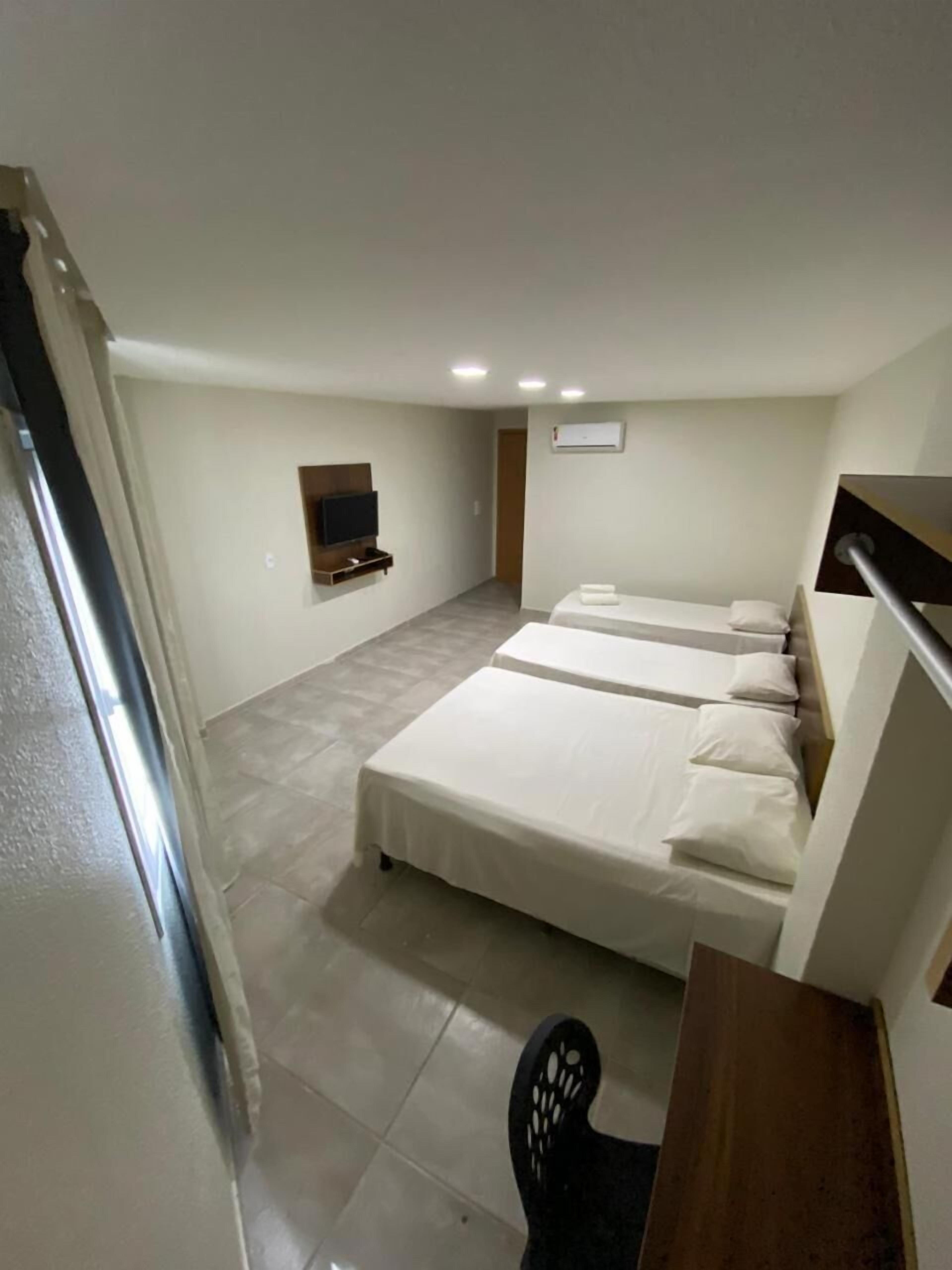 Una habitación de hotel moderna con una cama grande, un televisor montado en la pared y un escritorio con una silla.