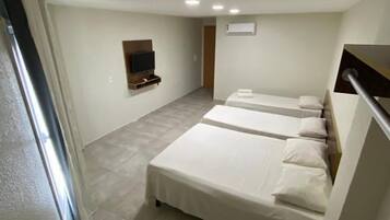 Una habitación de hotel moderna con una cama grande, un televisor montado en la pared y un escritorio con una silla.