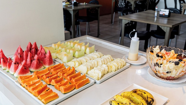 Un buffet proposant divers fruits et un saladier rempli de salade de fruits.