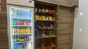 Un réfrigérateur à boissons, rempli de diverses boissons et collations, notamment de l’eau en bouteille, des sodas et des chips.