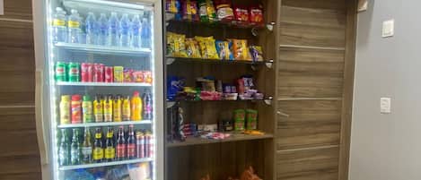A refrigerated beverage cooler stocked with various drinks and snacks, including bottled water, sodas, and chips.