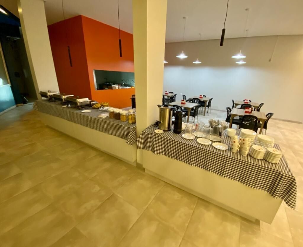 Un comedor moderno con manteles a cuadros, una barra larga con varios platos y una pared de acento anaranjada brillante.