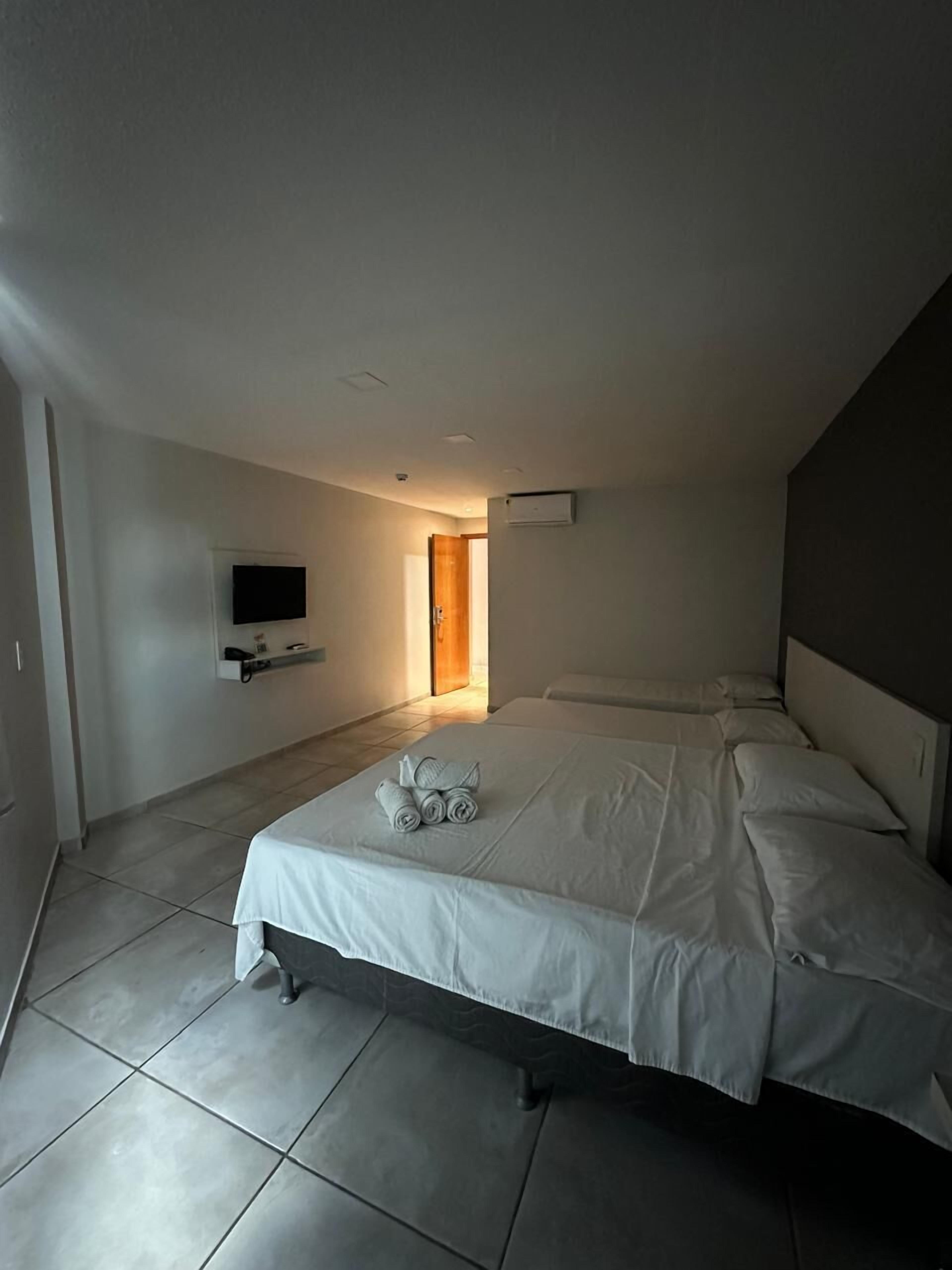 Habitación de hotel moderna con una cama grande, un televisor de pantalla plana en la pared y una mesita con toallas.
