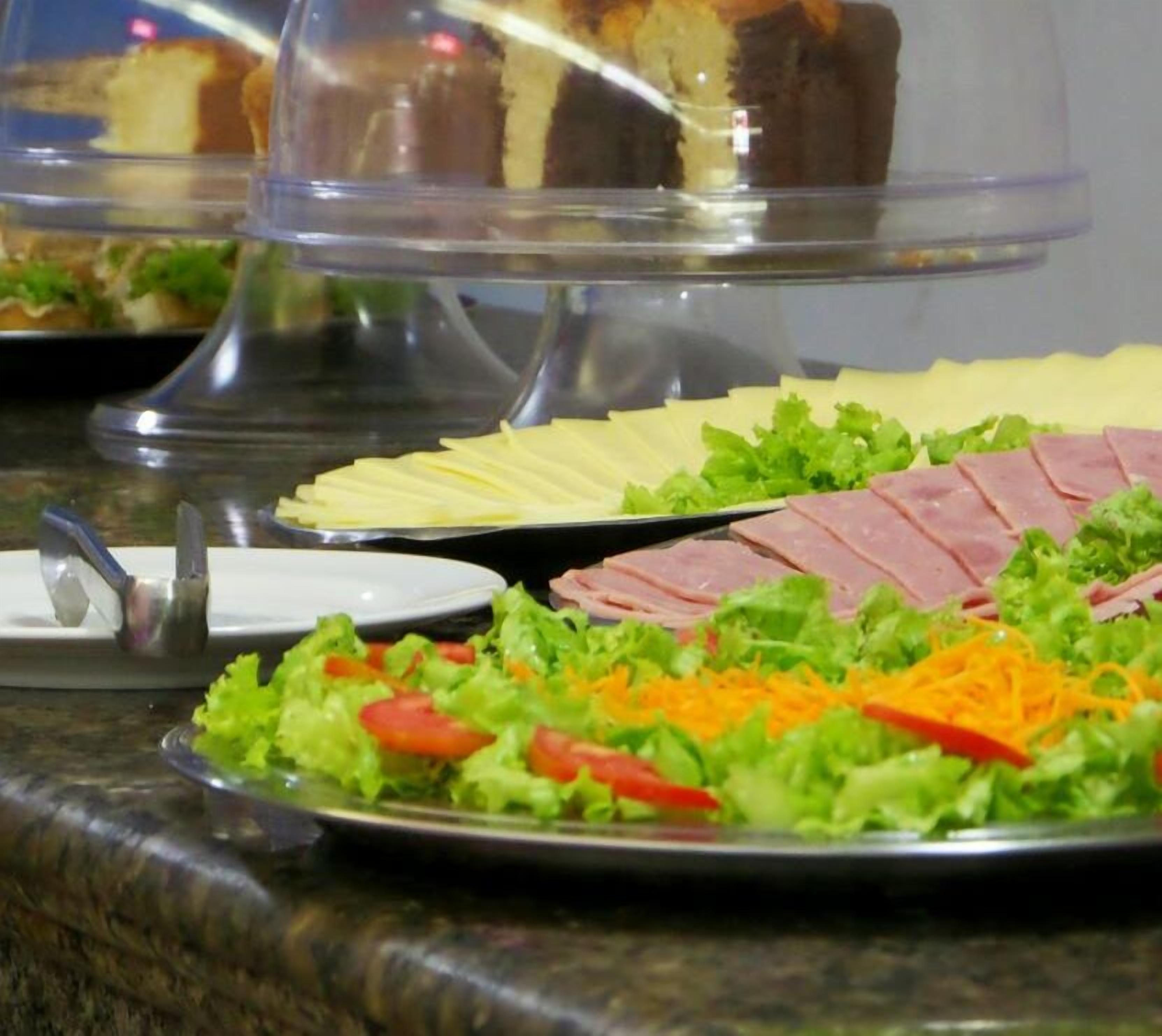 Un bufé con diversas opciones de comida, incluyendo carnes frías, quesos y ensaladas.