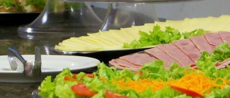 Un bufé con diversas opciones de comida, incluyendo carnes frías, quesos y ensaladas.