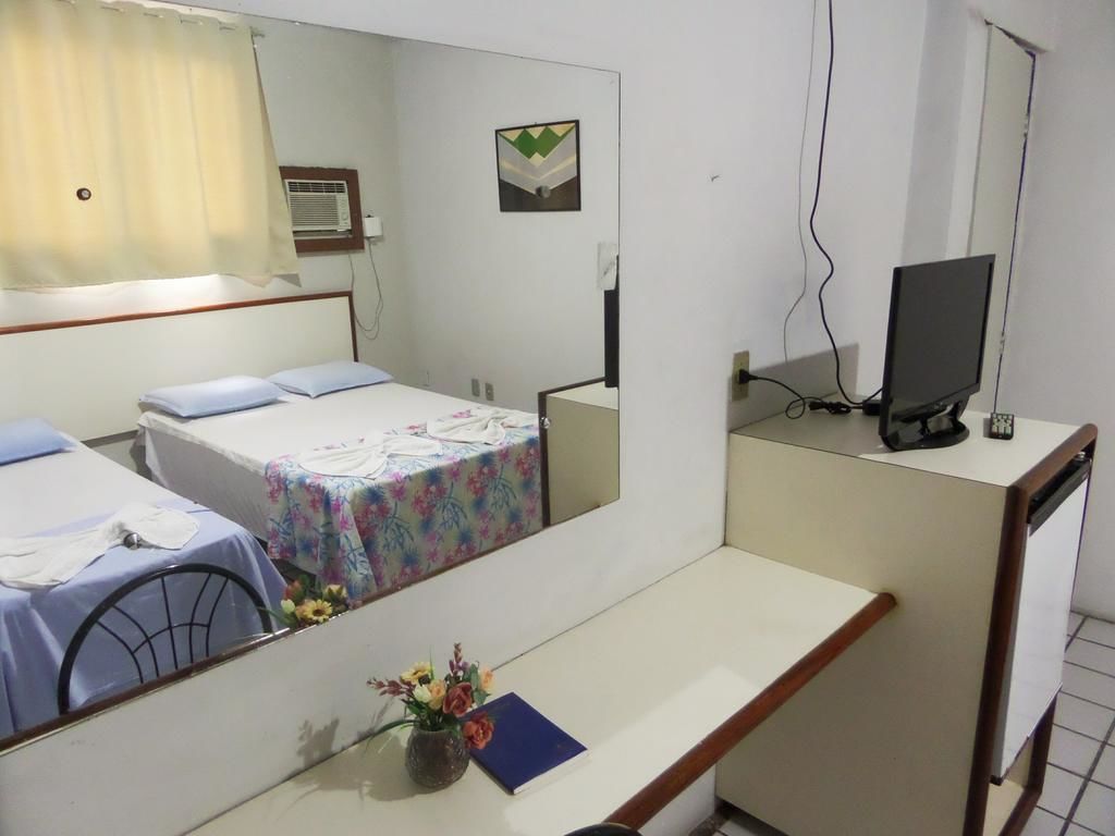 Une chambre d’hôtel avec deux lits, un bureau, une télévision et un miroir.