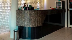 Un espace d’accueil doté d’un comptoir incurvé, d’une poubelle et d’un mur orné d’un motif géométrique.