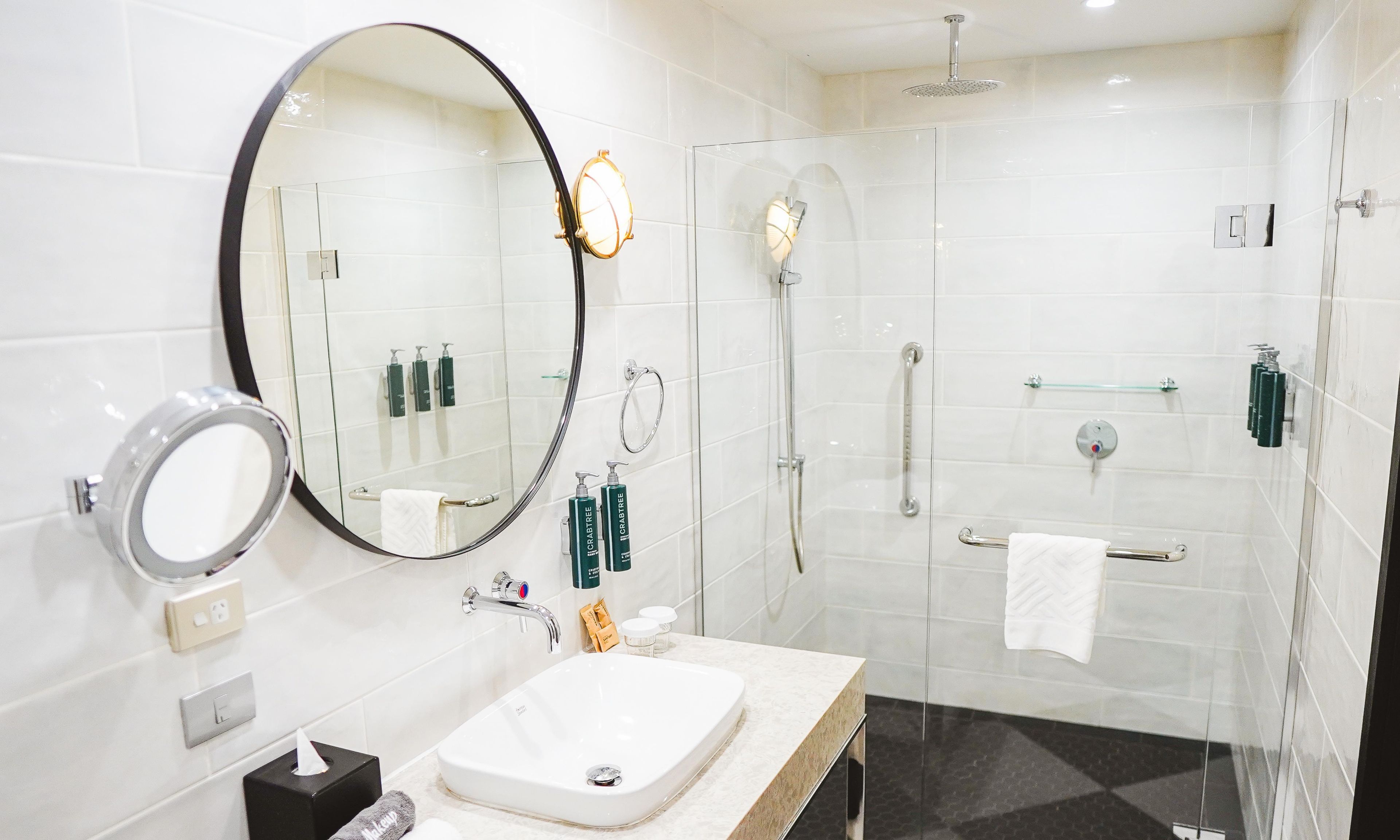 A modern bathroom with a large mirror, a sink, and a glass-enclosed shower area.