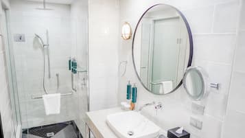 A modern bathroom with a glass shower enclosure, a white sink, and a large mirror.