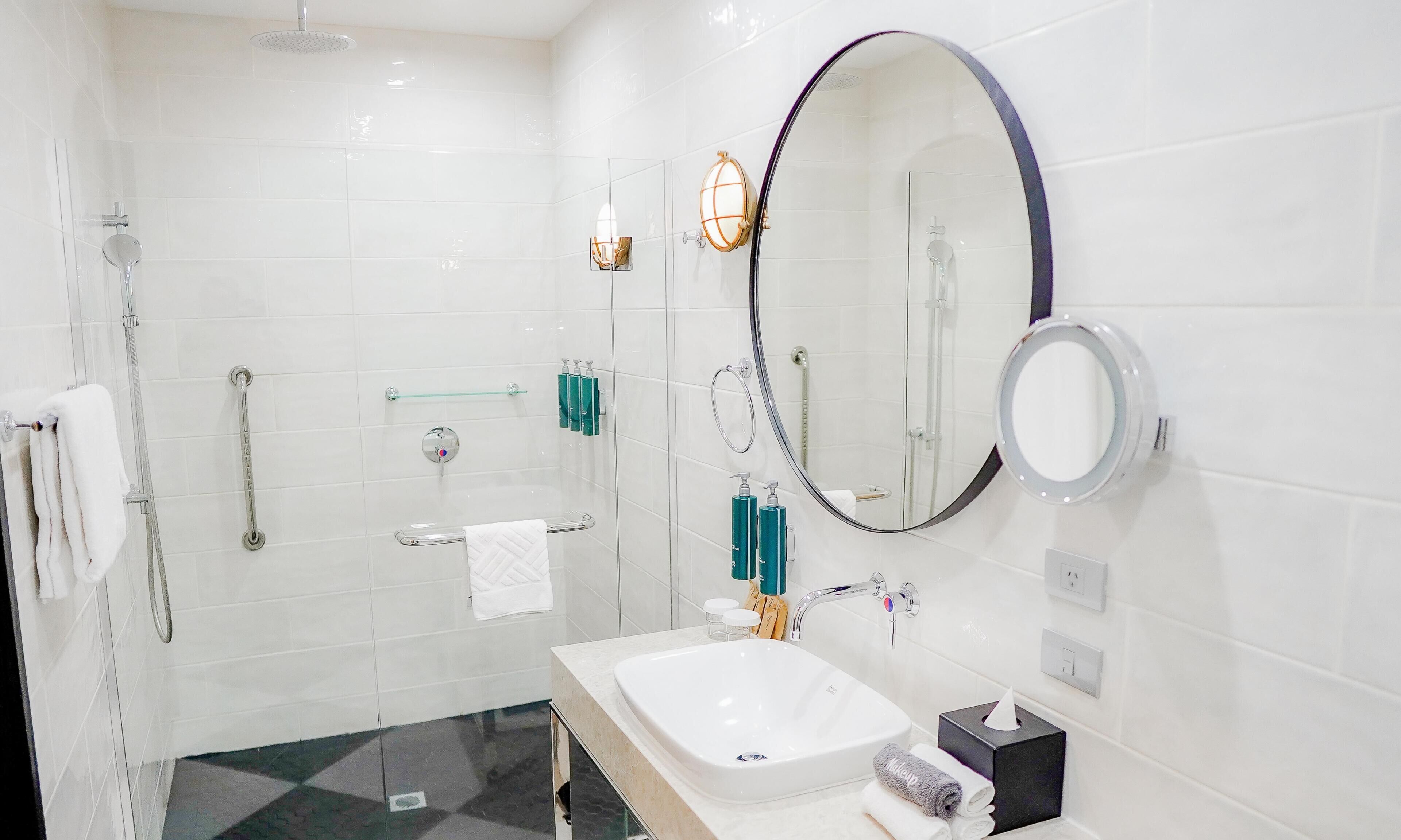 Un baño moderno con ducha de vidrio, tocador con lavabo y un espejo grande.