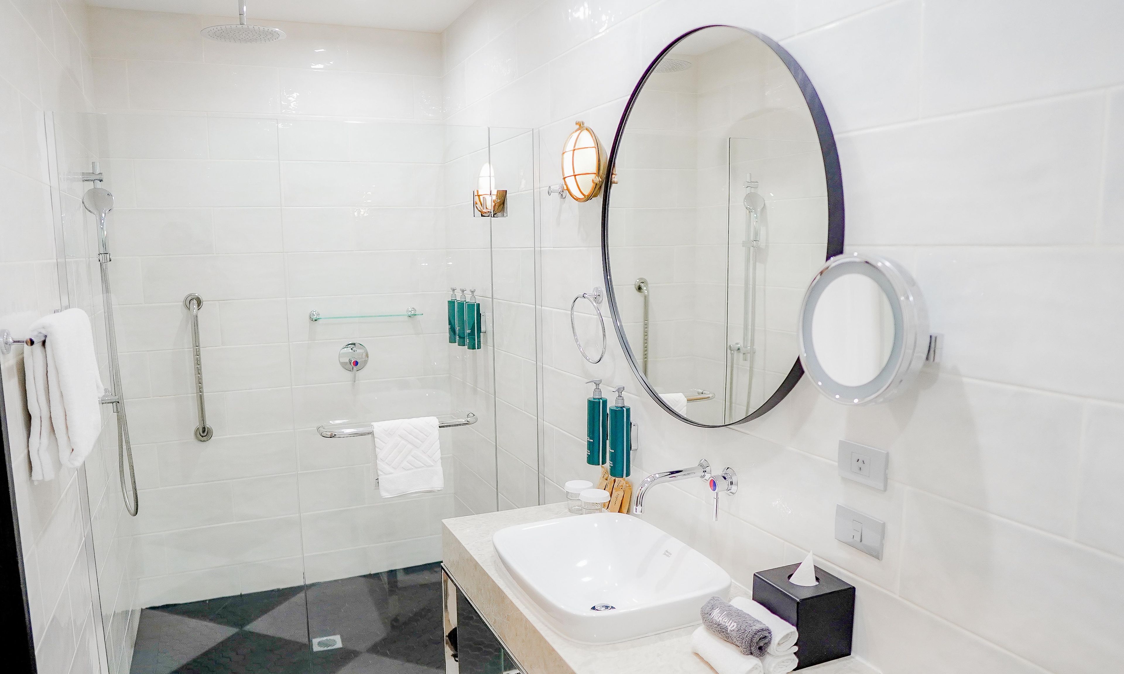 A modern bathroom with a glass-enclosed shower, a vanity with a sink, and a large mirror.