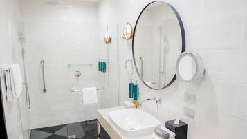 A modern bathroom with a glass-enclosed shower, a vanity with a sink, and a large mirror.