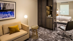 A hotel room with a sofa, a desk, a chair, a bed, and a large window. - DoubleTree by Hilton Wellington (Wellington)