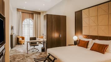 A hotel room with a large bed, a desk with a chair, a wardrobe, and a television.