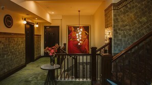 A hallway with a staircase, a painting, and a table with flowers. - DoubleTree by Hilton Wellington (Wellington)