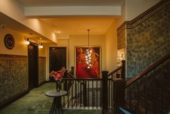 A hallway with a staircase, a painting, and a table with flowers. - DoubleTree by Hilton Wellington (Wellington)