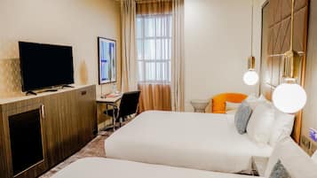 A hotel room with a bed, a desk, a television, and a window with curtains.