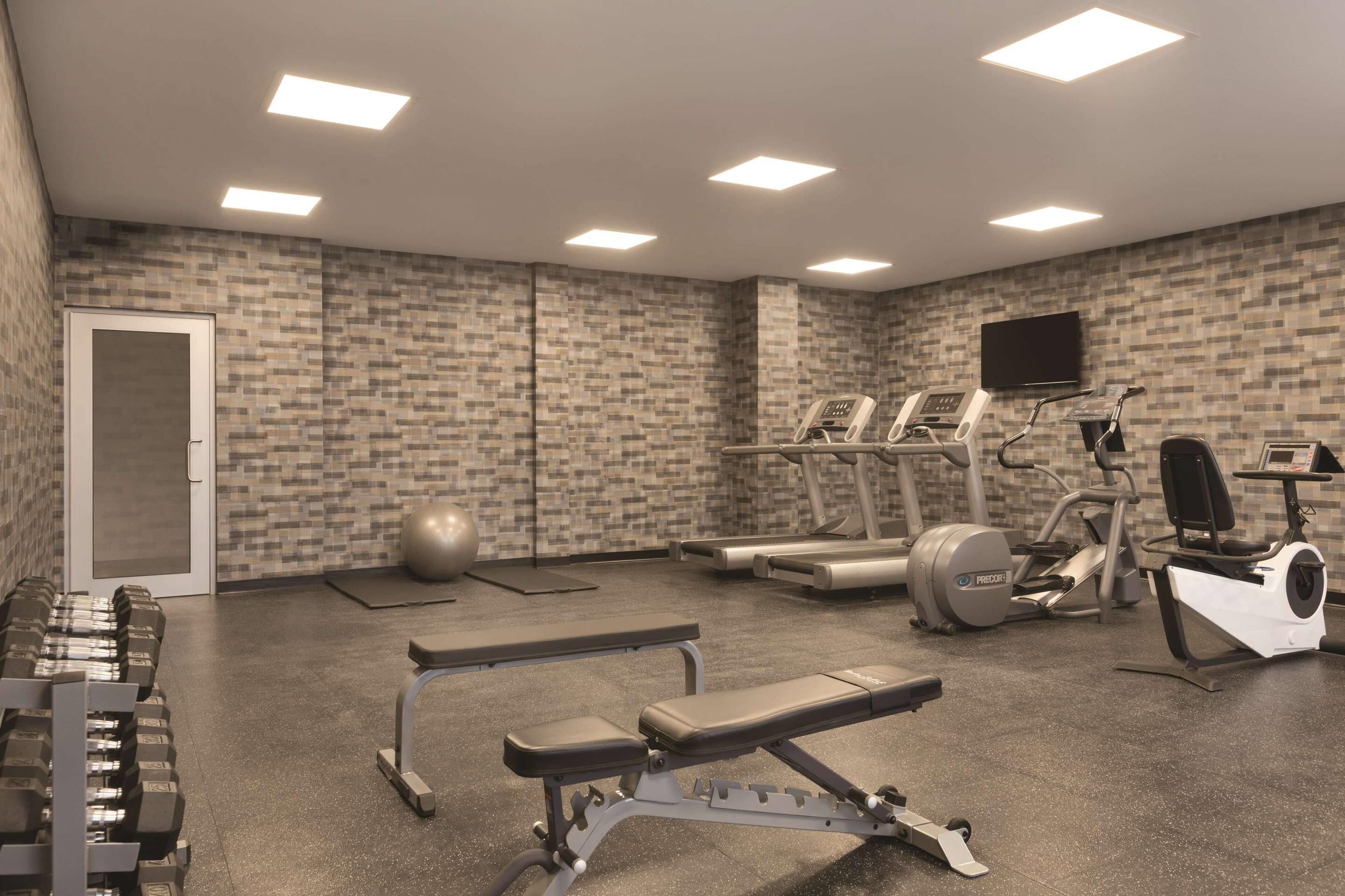 A gym with treadmills, elliptical machines, free weights, and exercise balls.