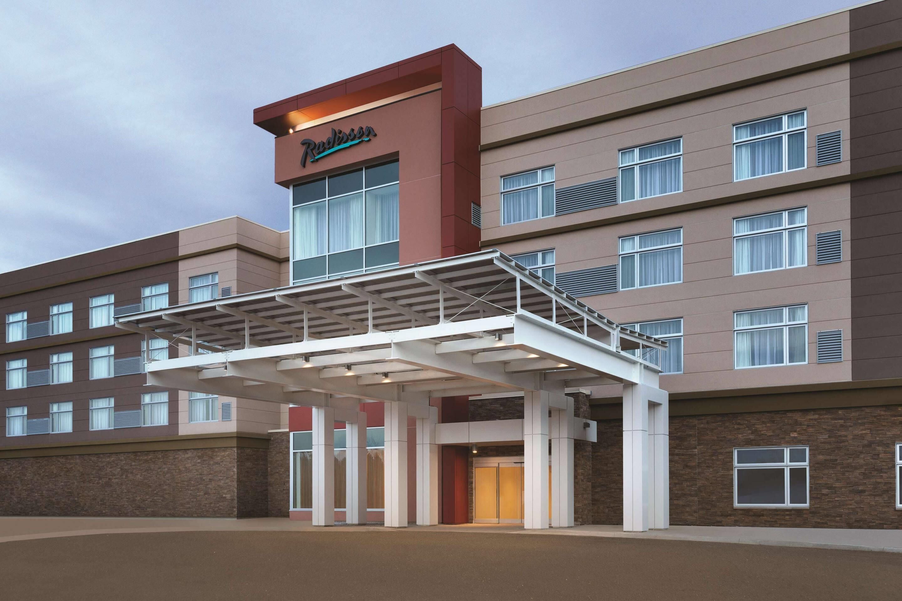 A modern hotel with a prominent 'Radisson' sign, a covered entrance, and multiple floors with windows.