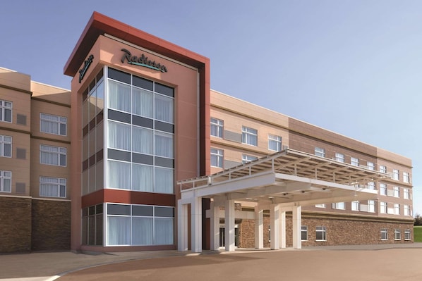 Hotel entrance with a covered walkway and large windows.