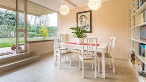 A dining area with a white table and chairs, a potted plant, and a bookshelf. - Villa Comfort Zone Tirrenia (Tirrenia)
