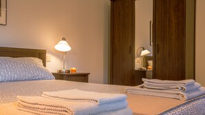 A neatly made bed with folded towels, a bedside lamp, and a wooden wardrobe in a hotel room. - Villa Comfort Zone Tirrenia (Tirrenia)