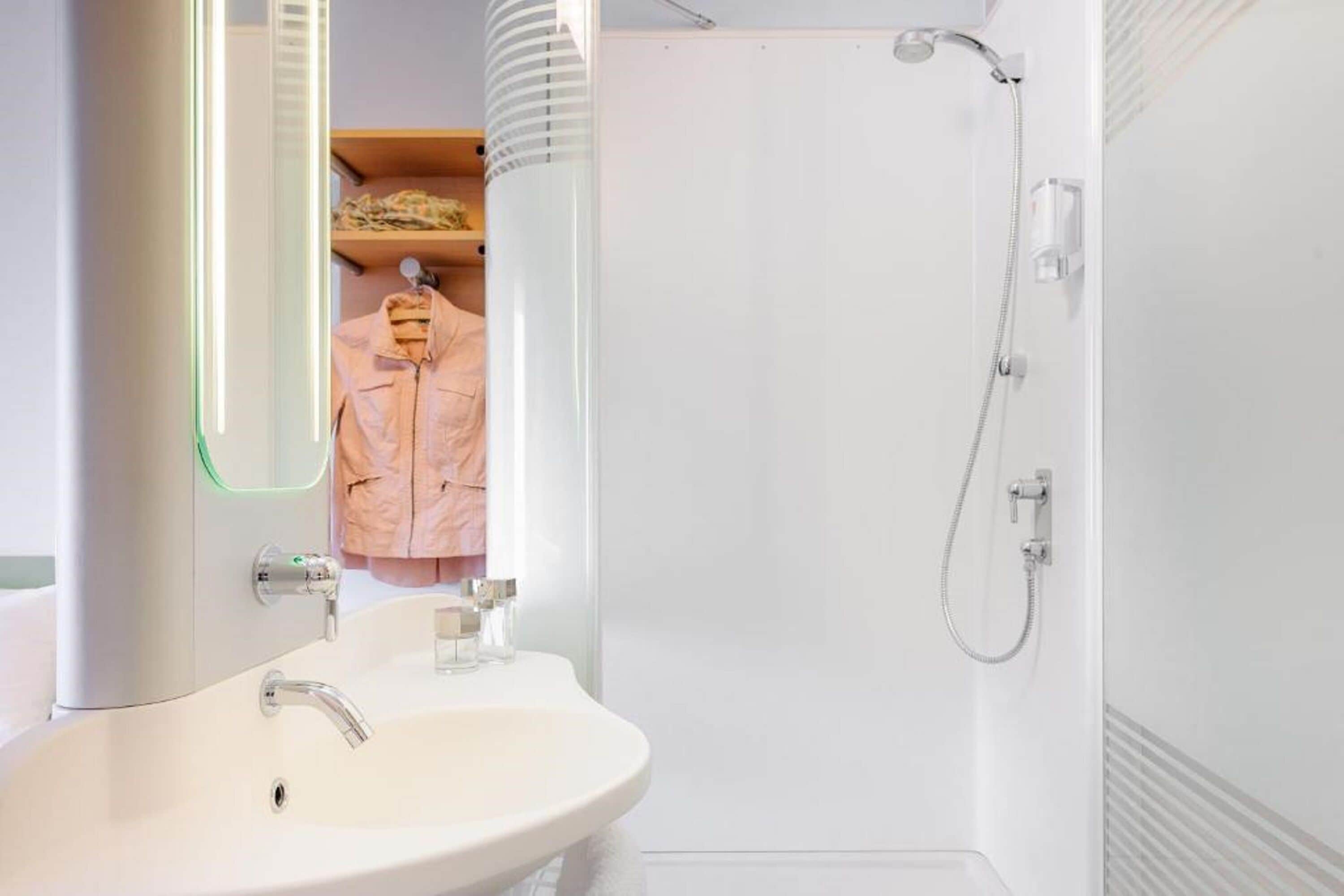 A bathroom with a white sink, mirror, and shower.