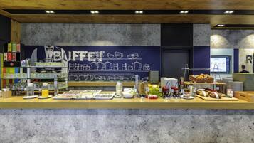Un bufé de desayuno con una variedad de alimentos y una pared con una ilustración sobre café.