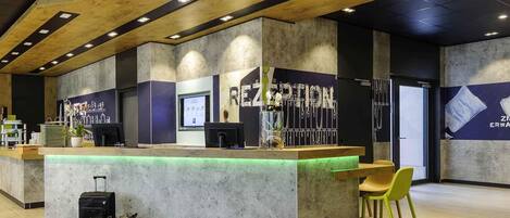 A reception area with a wooden counter, a computer, and a seating area with chairs.