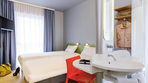 A hotel room with a bed, a desk, a chair, a sink, and a mirror. - Ibis Budget Bamberg (Bamberg)