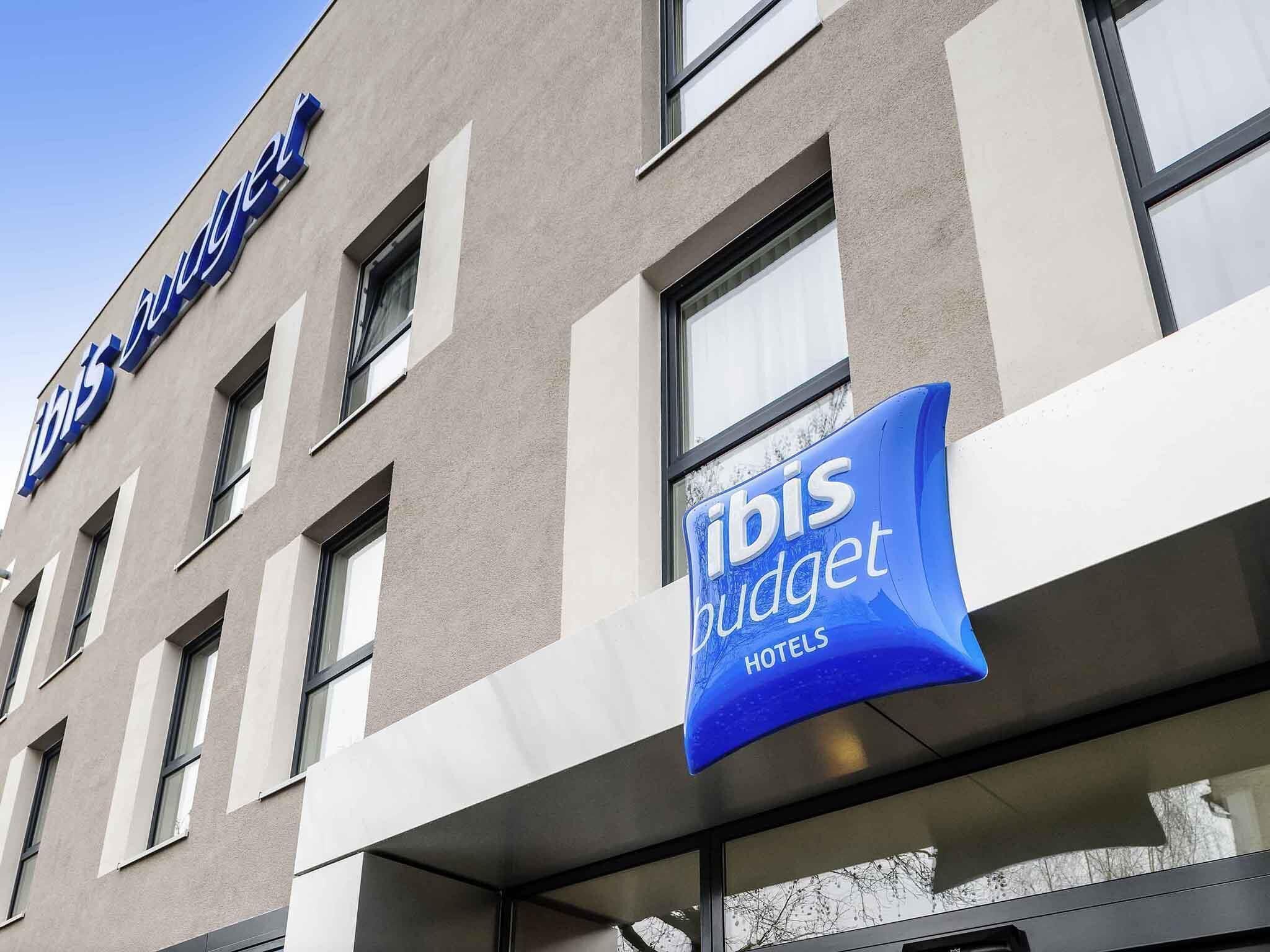 A hotel building with a sign for 'ibis budget hotels' and a clear sky.